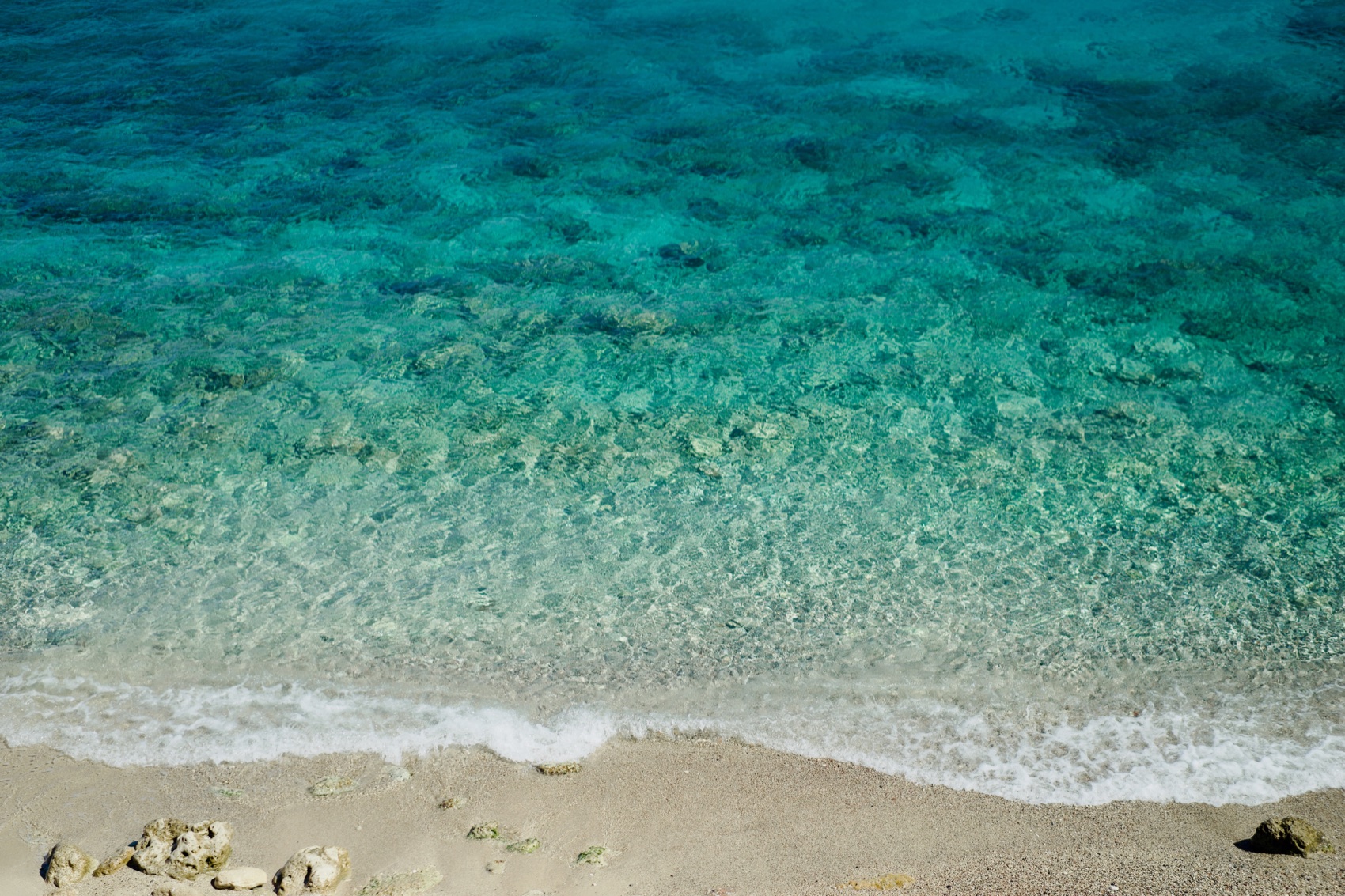 Shallow turquoise water washing over a light sand beach